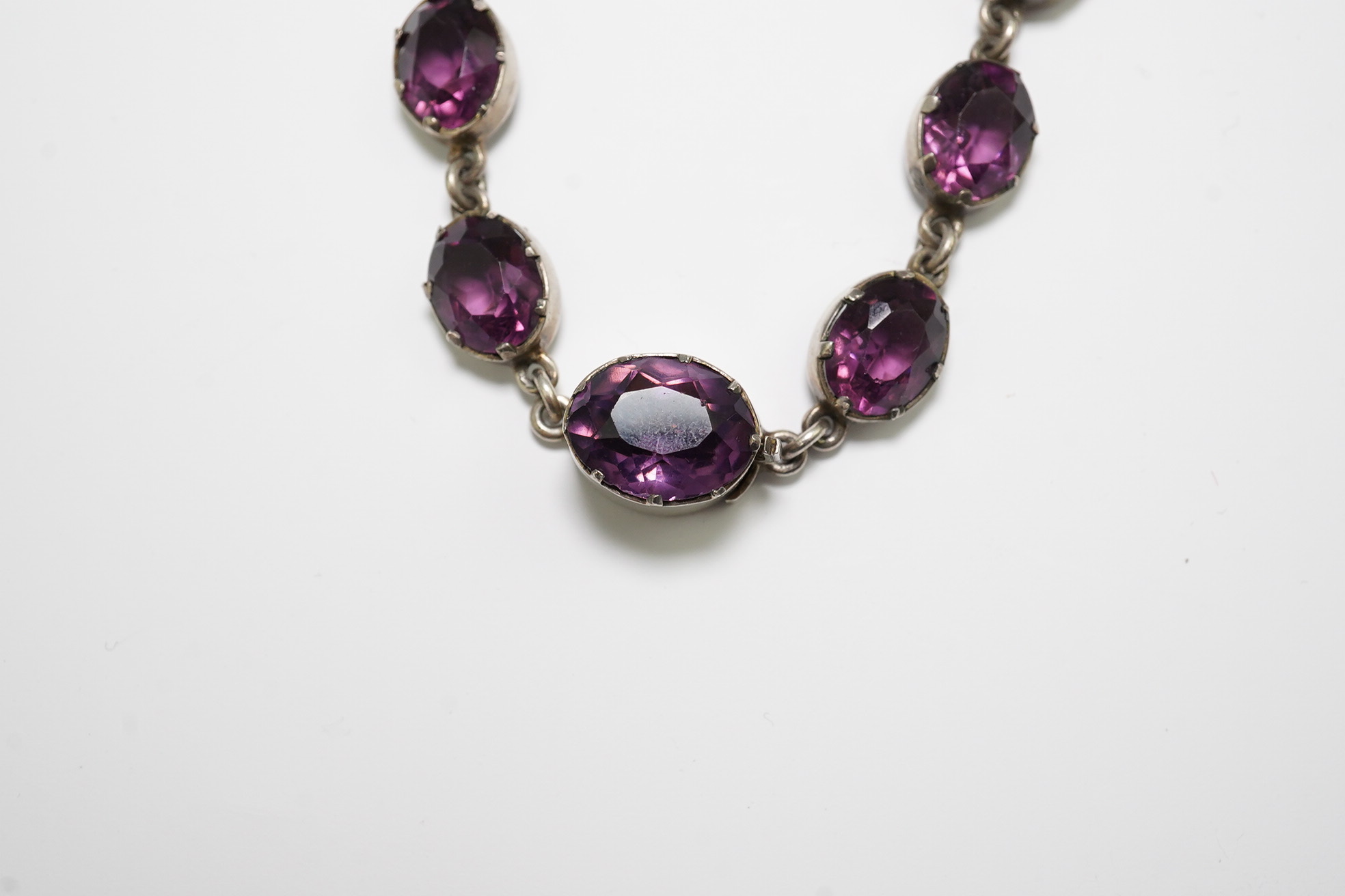 A Victorian silver and graduated oval cut amethyst paste set riviere necklace